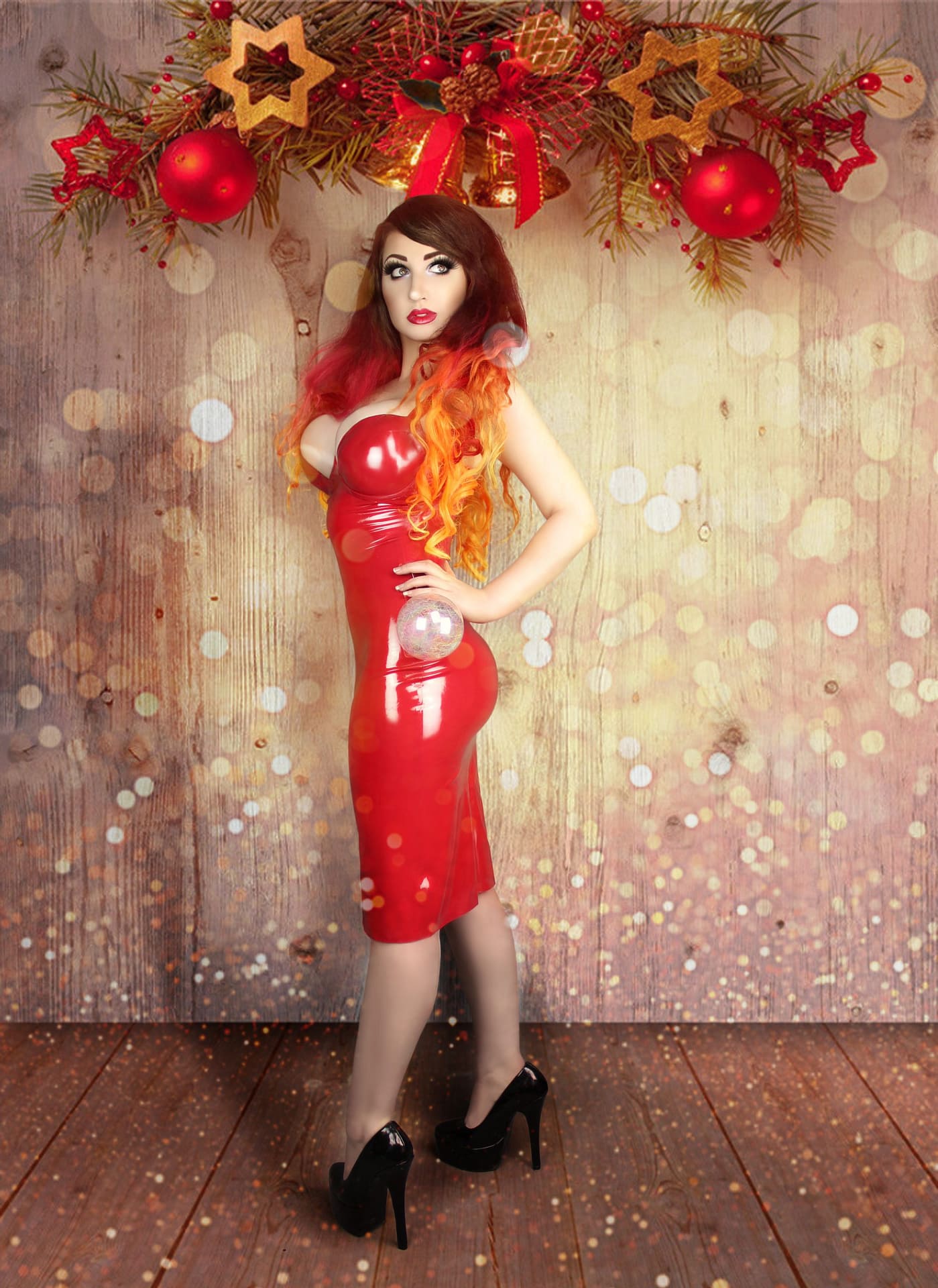 latex christmas dress pretty new year blonde girl posing in black latex catsuit and red funny christmas  dress on background of her white home with snow and trees Stock Photo